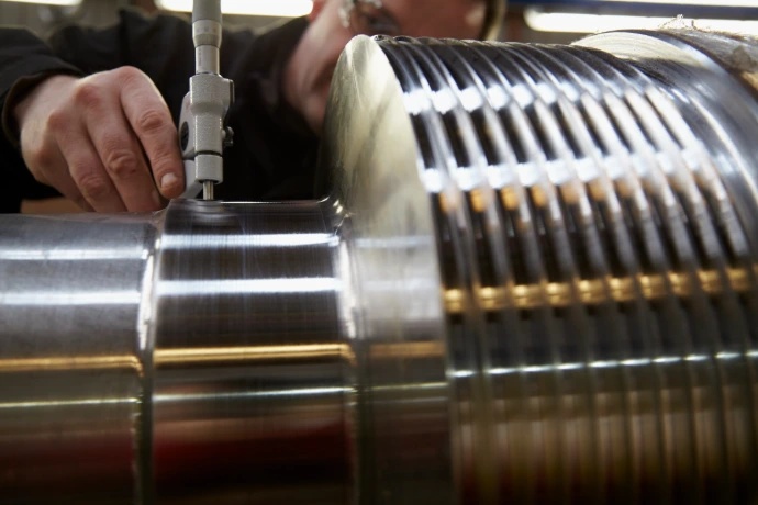 Roval technician measuring shaft geometry for precision calender roll filling