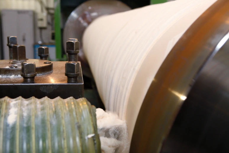 Close-up of CNC turning operation on compressed fiber calender roll cover